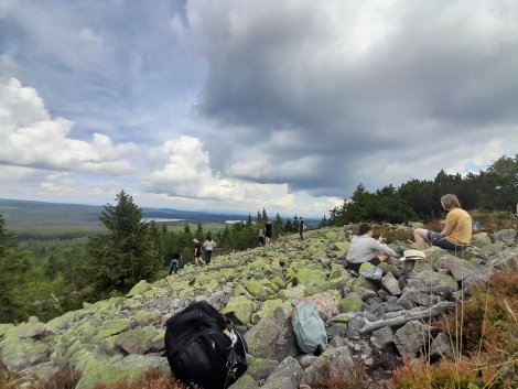 Menschen sitzen auf Steinen, blicken weit übers Land